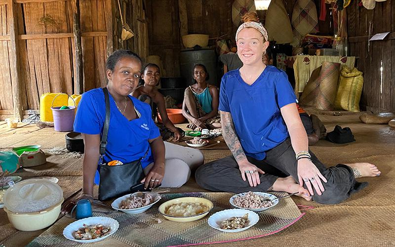 澳门新普京注册 alumna and Peace Corps volunteer Mackenzie Hafer with a family at mealtime in Madagascar